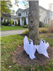 ghost decorations by a tree with a house in the background