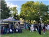 People and police officers near police department tent in grassy park area