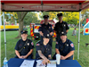 Firefighters seated under tent in park posing for photo