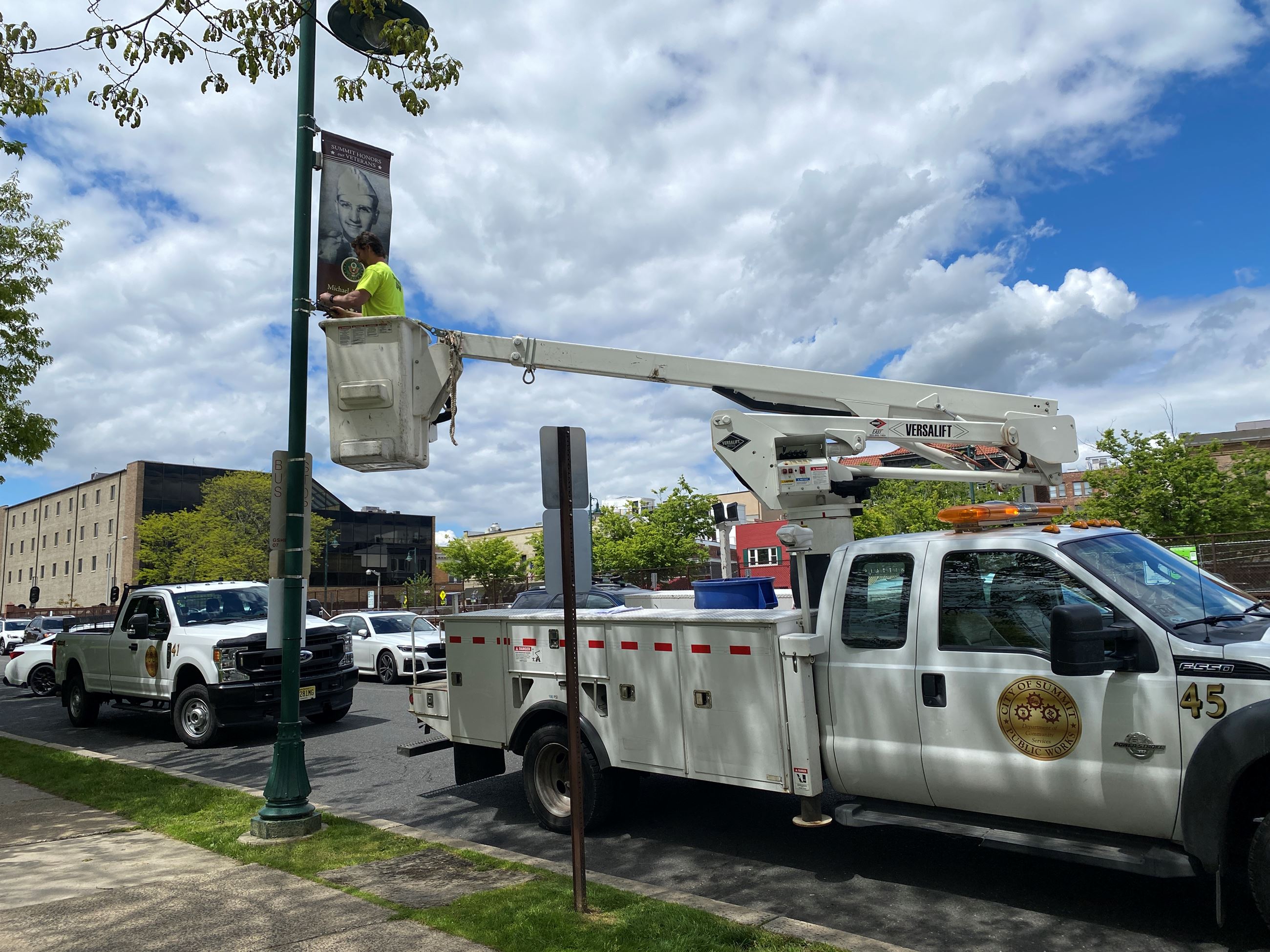 DPW employee in truck hanging a banner from a lamppost