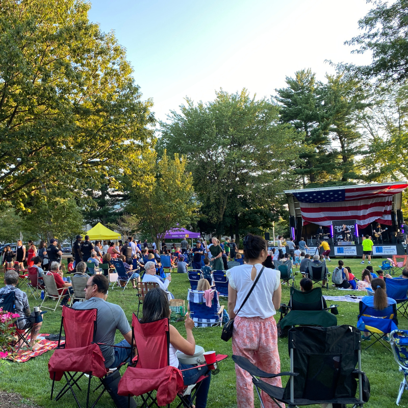 summit village green during a concert with lots of people sitting in chairs facing a stage