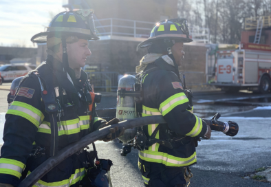 firefighters in gear with building in the background