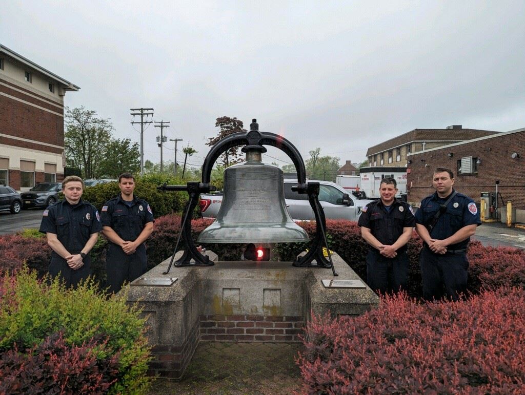 group photo of firefighters gathered around memorial bell