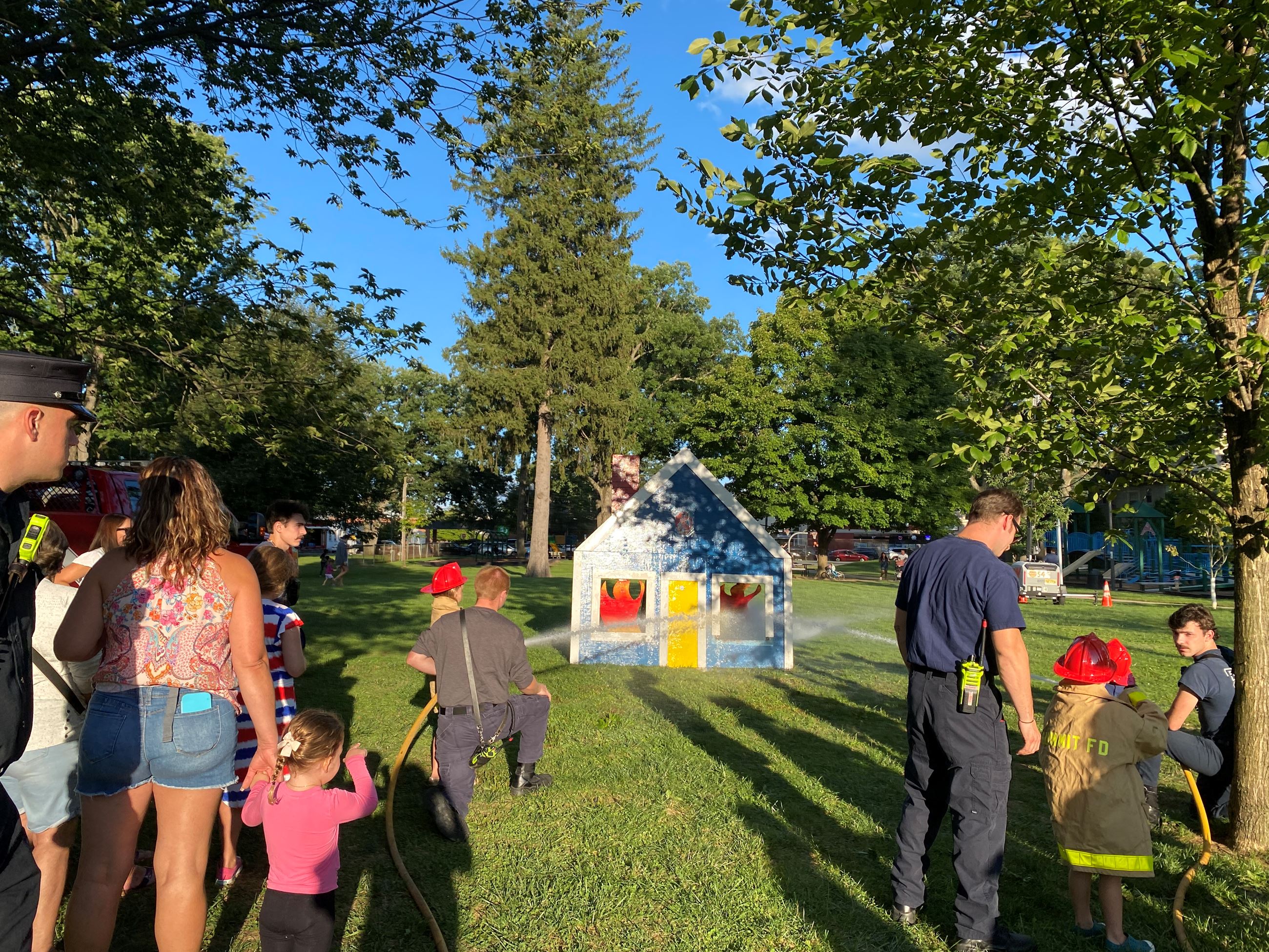 Firefighters and children near firefighter demonstration in park