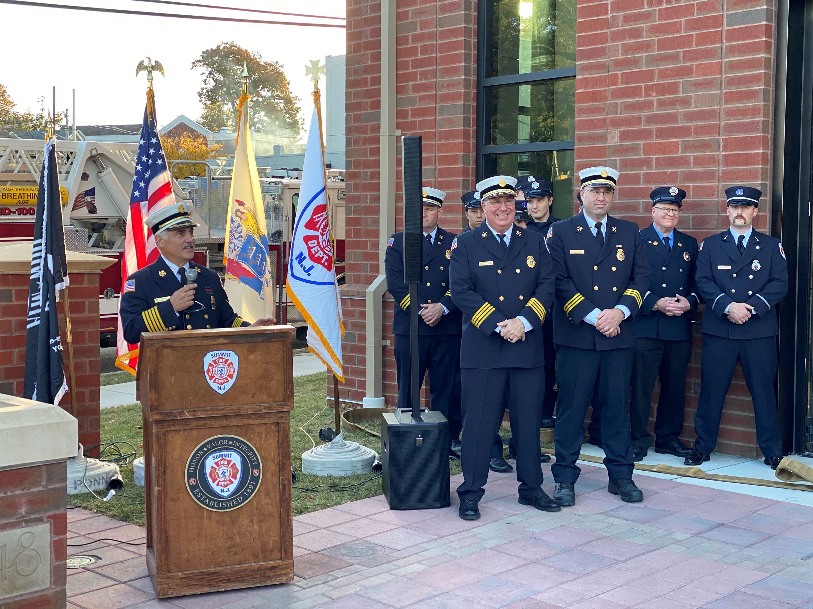 members of summit nj fire department at and near podium with flags in the background