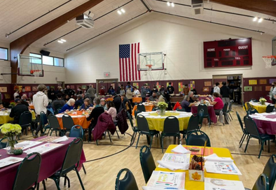 image of large gym with people sitting and eating together at tables