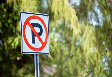 image of no parking sign with blurred trees in the background