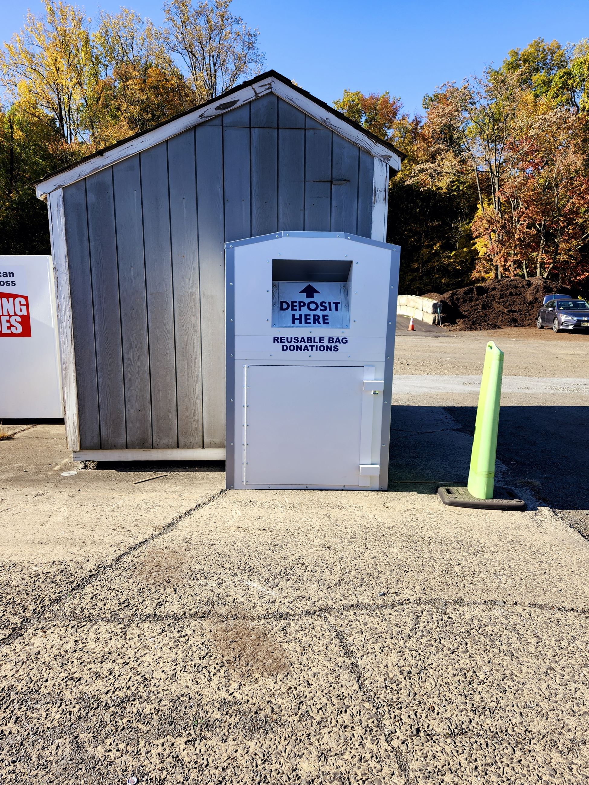 Collection bin next to small gray shed at municipal disposal center